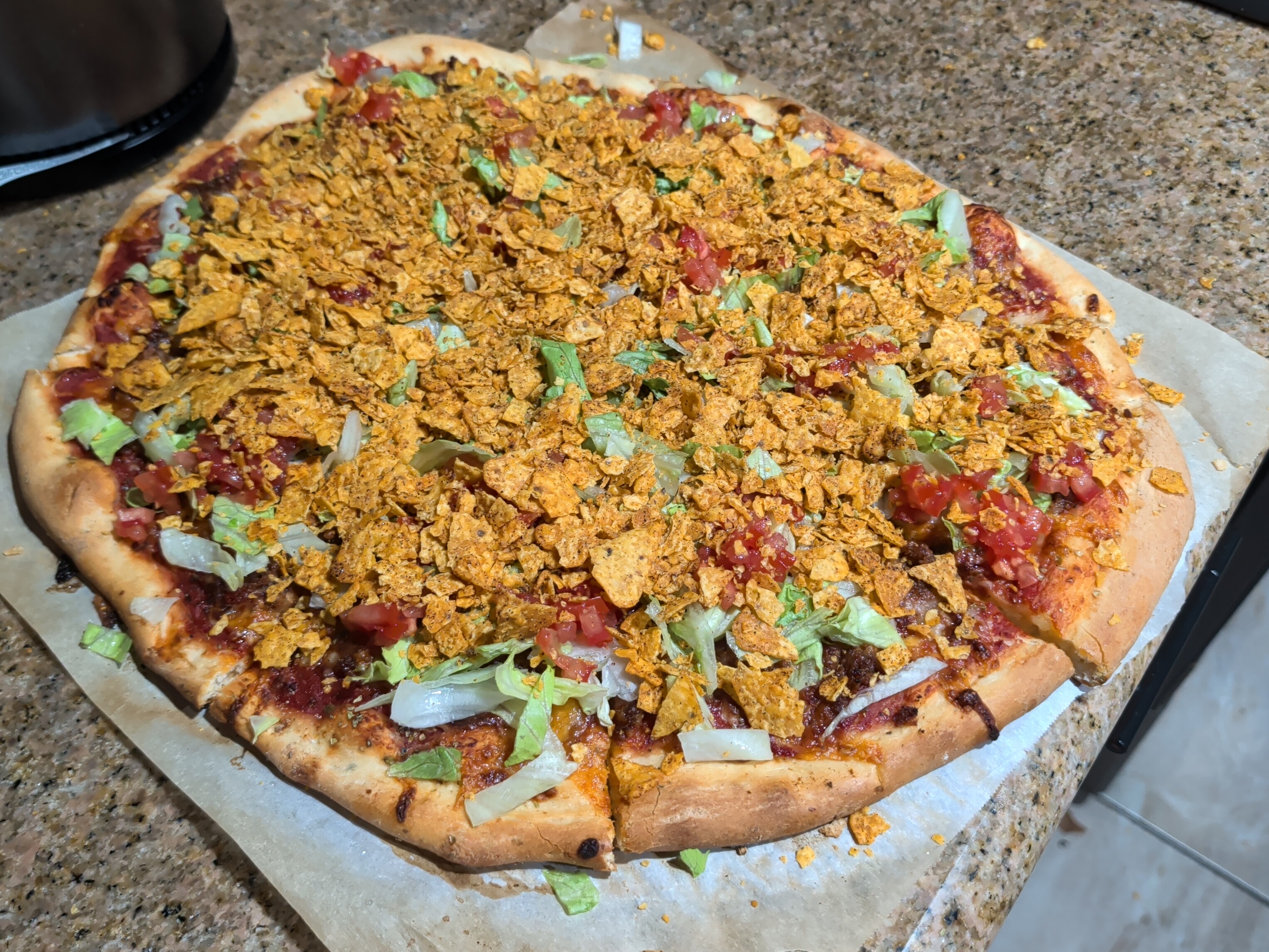 Taco pizza with seasoned sausage, lettuce, tomatoes and crushed taco chips